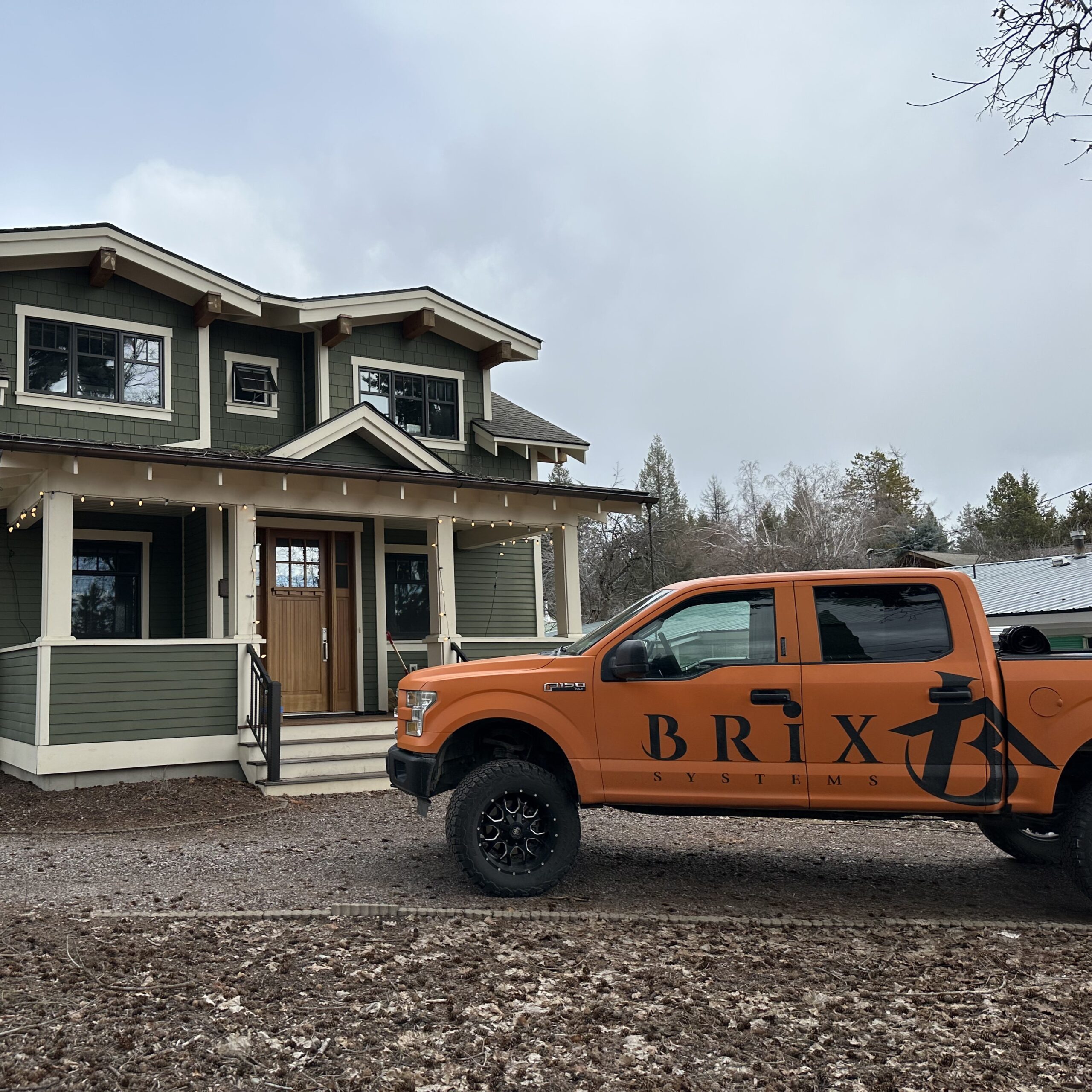 an orange Brix Systems Company truck in front of a green house