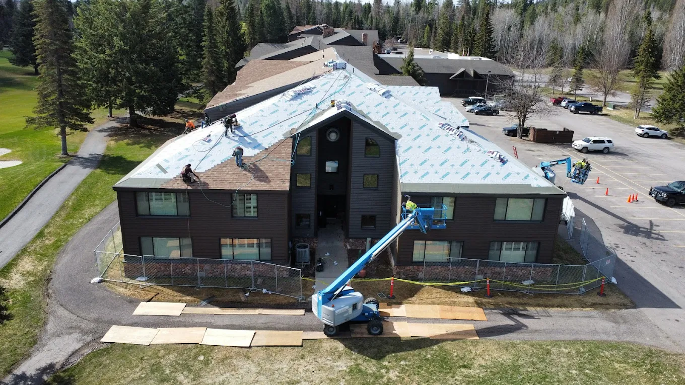 Roofers installing new shingle roof on a commercial building